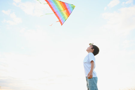 Boy is running with a kite during the day in the field.の写真素材