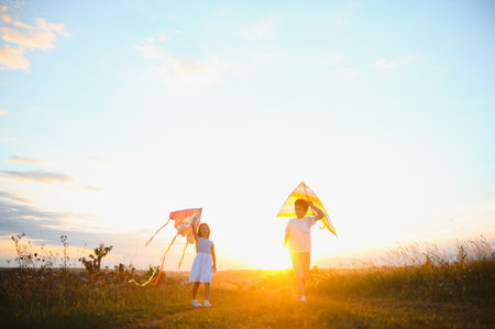 Children launch a kite in the field at sunset.の写真素材
