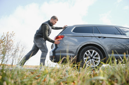Man pushing a broken car down the rock road.の写真素材