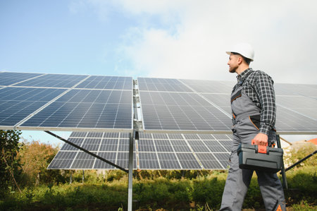 Expert is inspecting the quality of a solar battery. Worker in uniform and helmet with equipment. Ecology power conservation conceptの写真素材