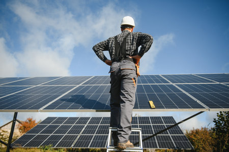 Male worker in uniform outdoors with solar batteries on a sunny dayの写真素材