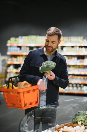 Young man buying groceries at the supermarket. Other customers background. consumerism conceptの写真素材