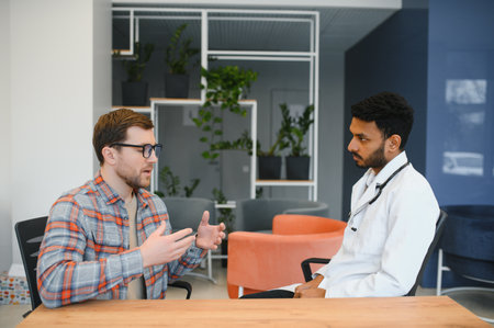 Indian doctor in white gown seeing patients in officeの写真素材
