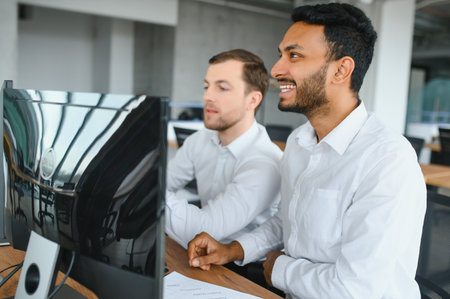 Two men traders sitting at desk at office together monitoring stocks data candle charts on screen analyzing price flow smiling cheerful having profit teamwork concept.の写真素材