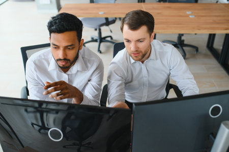 Two successful trader sitting in office and looking at screen, checking cryptocurrency information...