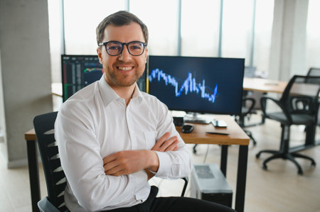 Man trader in formalwear sitting at desk in frot of monitors with charts and data at office