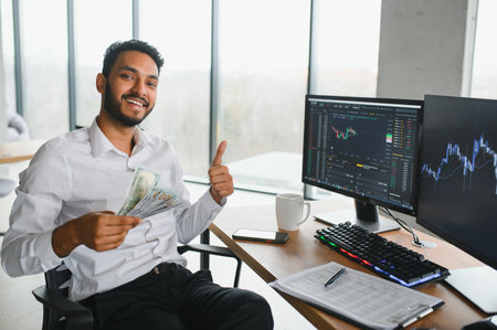 Thoughtful concentrated indian business man entrepreneur investor manager using computer, watching webinar working in office analyzing online data market thinking doing web research looking at laptopの写真素材