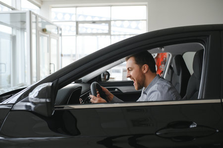 Young man is choosing a new vehicle in car dealershipの写真素材