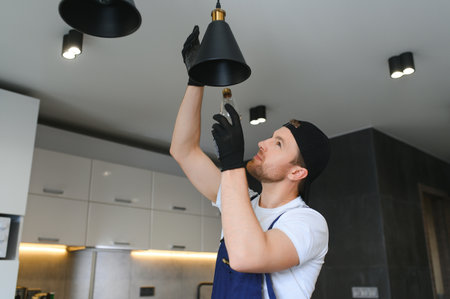 A male electrician changes the light bulbs in the ceiling light. men's household duties. care of electrical appliances at home.の写真素材