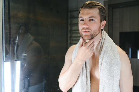 Handsome shirtless man looking in the mirror in the bathroom.の写真素材