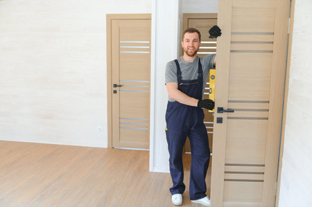 handsome young man installing a door in a new house construction siteの写真素材