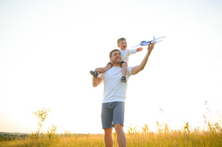 Dad with his son at sunset in nature. A father plays with toy airplanes with his son at sunset. father's day.の写真素材