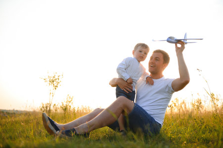 father's day. dad and baby son playing together outdoors plane.の写真素材