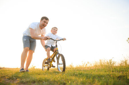 father's day. Dad and son playing together outdoors on a summer. Happy family, father, son at sunsetの写真素材