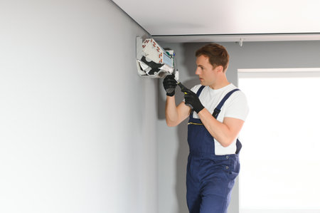 technician service checking and repairing air conditioner indoors.
