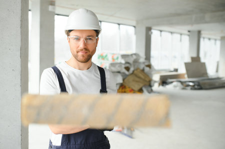 Portrait of positive, handsome young male builder in hard hat