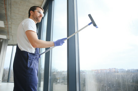 Male worker washing window glass.