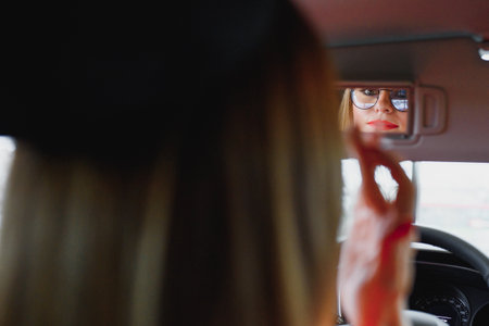 young woman looking in the rearview mirror of a carの写真素材