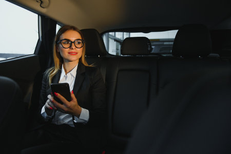 Some sort of interesting information. Smart businesswoman sits at backseat of the luxury car with black interior.の写真素材
