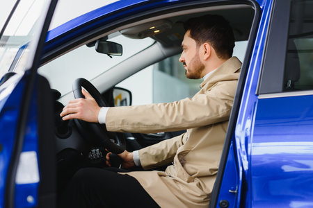 Handsome bearded businessman is sitting in a new car in car dealership