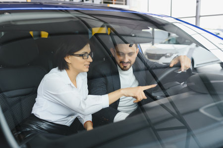 Handsome bearded businessman is sitting in a new car in car dealership
