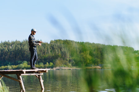 A man catches a fish on a spinning fishing in the summerの写真素材