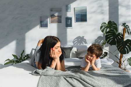 Portrait of a happy mother and her children son lying on a bedの写真素材