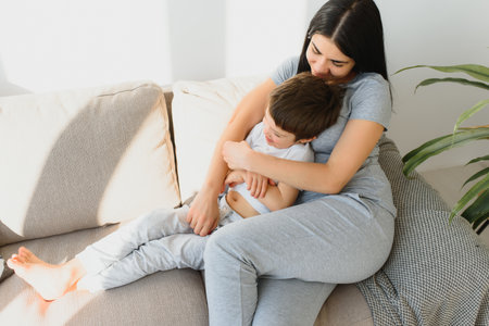 Young mother with her 4 years old little son dressed in pajamas are relaxing and playing in the bed at the weekend together, lazy morning, warm and cozy scene.の写真素材
