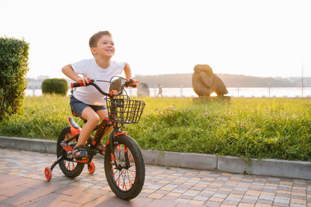 children on a bicycle at asphalt road in the early morning. Little boy learns to ride a bike in the park. Happy smiling child, riding a cyclingの写真素材