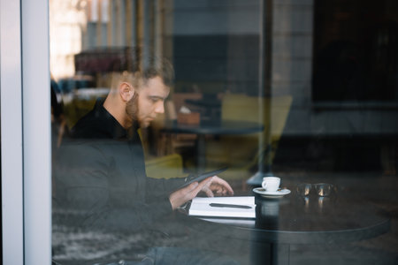 Young successful businessman working on a laptop while sitting in a cafe.の写真素材