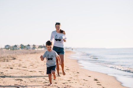 Mother and son playing on the beach at the sunset time. Concept of friendly family.の写真素材