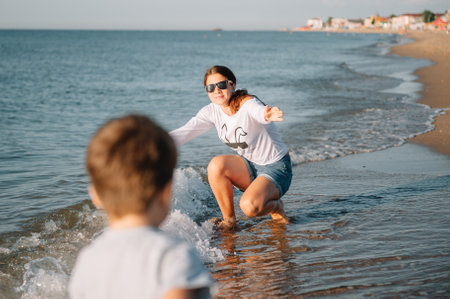 Mother and son playing on the beach at the sunset time. concept of friendly familyの写真素材