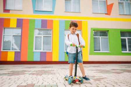 Boy goes to school on a scooter. Children back to school scoote.Childschool riding a scooter. back...