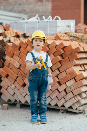 Architect in helmet writing something near new building. little cute boy on the building as an architect.の写真素材