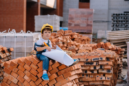 Architect in helmet writing something near new building. little cute boy on the building as an architect.の写真素材