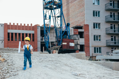 Architect in helmet writing something near new building. little cute boy on the building as an...
