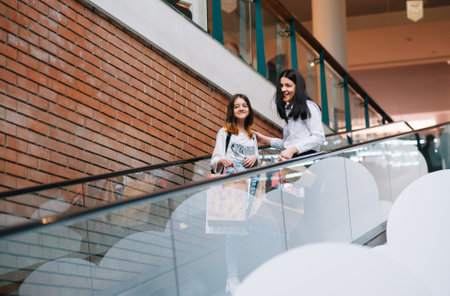 Beautiful young mom and teenage daughter are holding shopping bags and smiling while doing shopping in mall. family shopping.の写真素材