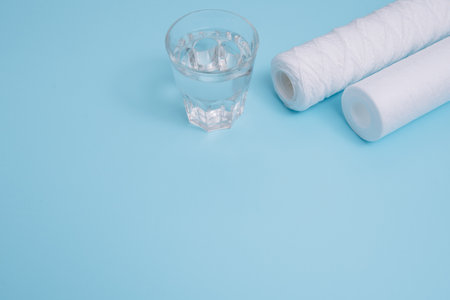 water filters. Carbon cartridges and a glass on a blue background. Household filtration system.の写真素材