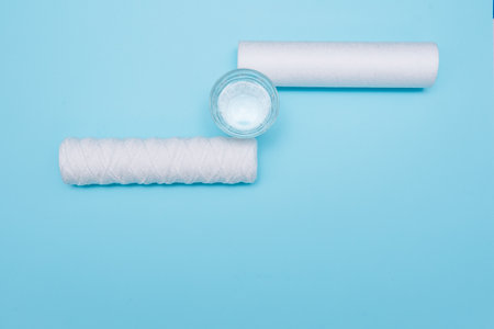 water filters. Carbon cartridges and a glass with water on a blue background. Household filtration system.の写真素材