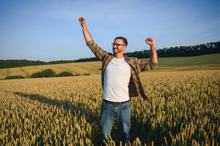 Happy farmer proudly standing in wheat field. Rich harvest of cultivated cereal crop