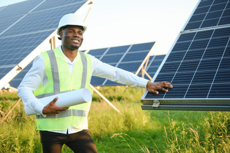 Close up portrait of handsome young African American craftsman a protective helmet. Happy man in overalls posing at camera smiling. slow motionの写真素材
