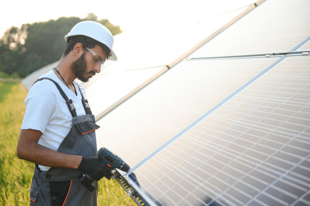 Indian man in uniform working near solar panel