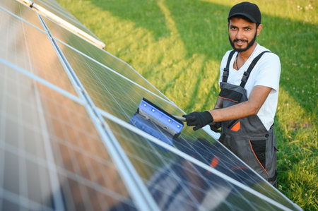 Indian handyman cleaning solar panels form dust and dirtの写真素材