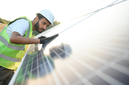 Male arab engineer standing on field with rows of solar panelsの写真素材