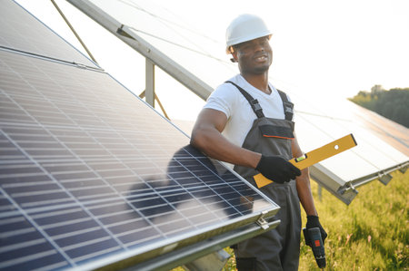 African American engineer maintaining solar cell panels. Technician working outdoor on ecological...