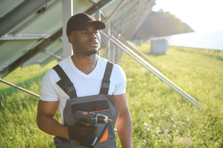 Portrait of african american electrician engineer in safety helmet and uniform installing solar panelsの写真素材