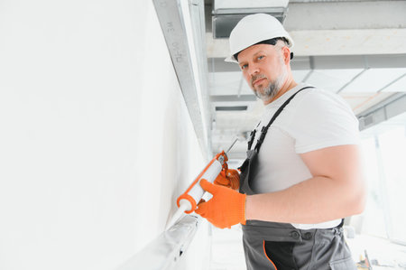 The builder fills the seams on the wall with sealed silicone.