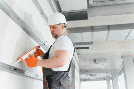 The builder fills the seam between plasterboard plates and silicone gun.の写真素材