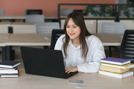 A cute schoolgirl is sitting at a desk at school. The concept of schoolingの写真素材