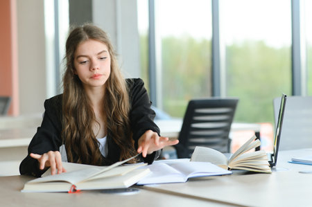 Teen girl studying with textbook writing essay learning in classroomの写真素材